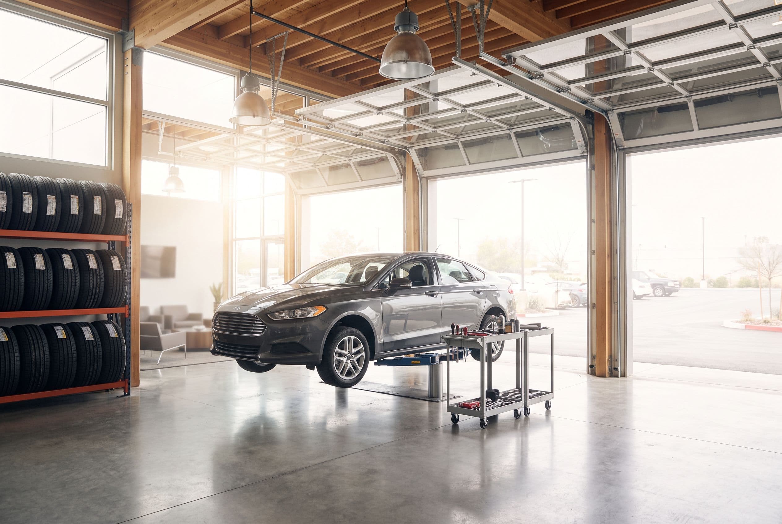 A tire and quick-service shop, cars moving in and out of open bays, stacks of tires lit in cool tones.